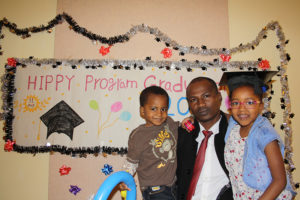 Father with son and daughter in front of graduation sign