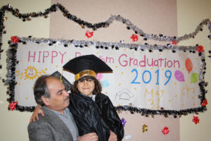 Father and daughter in front of graduation sign