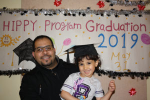 Father and daughter in front of graduation sign