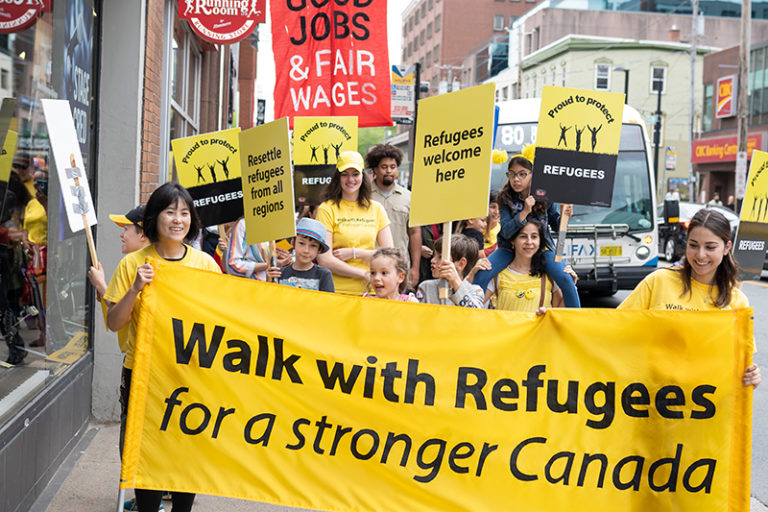 People carrying the Walk with Refugees banner and signs