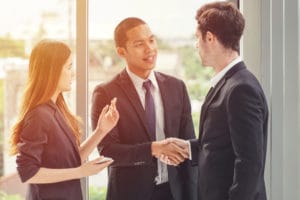 An immigrant youth wearing a suit and shaking hands with co-worker