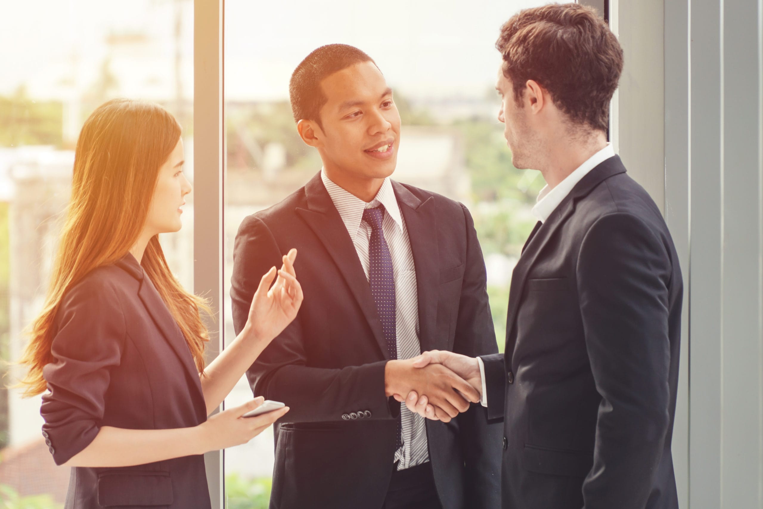 An immigrant youth wearing a suit and shaking hands with co-worker