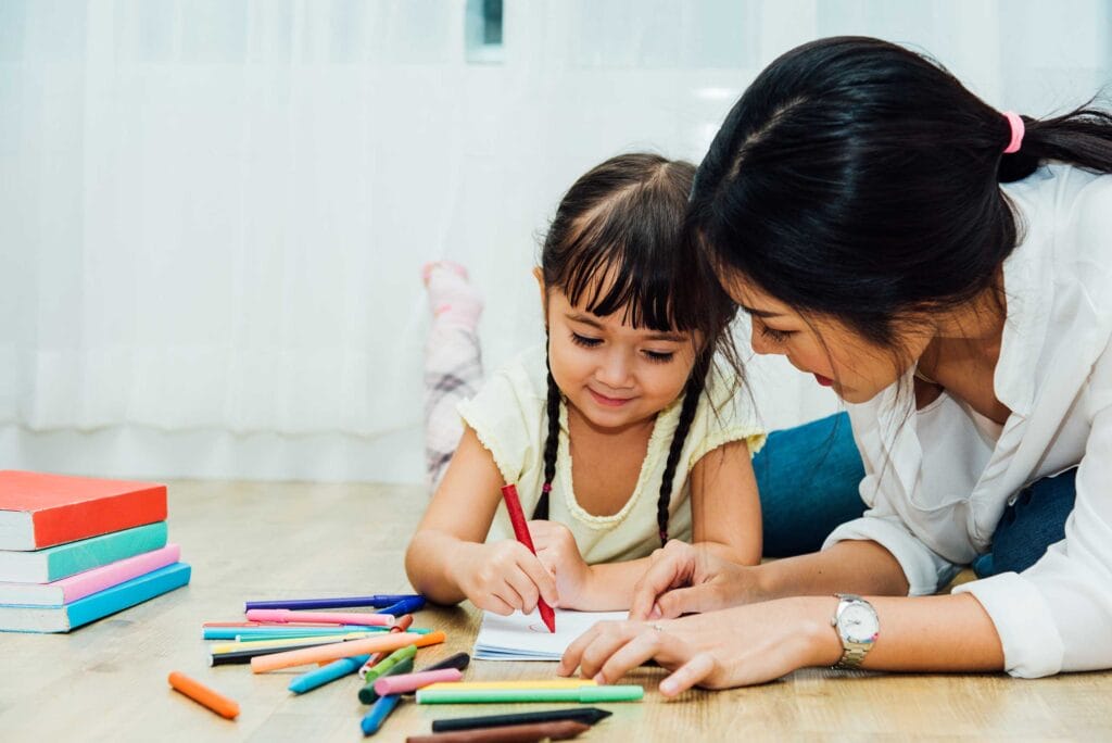 A parent woman teaching her daughter to write/draw
