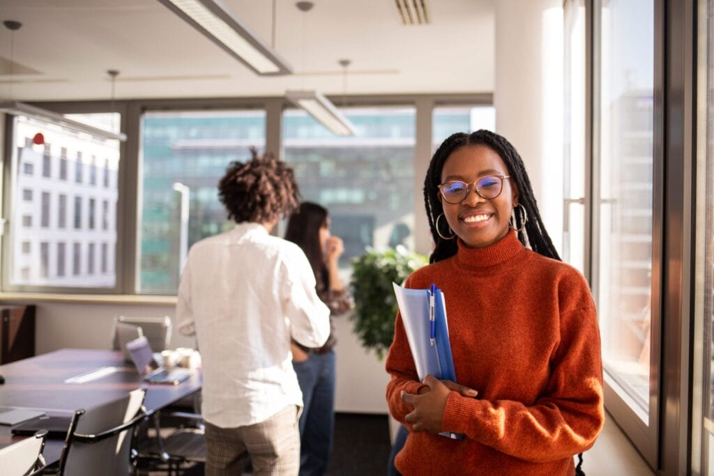An immigrant youth, smiling, and holding a folder of documents