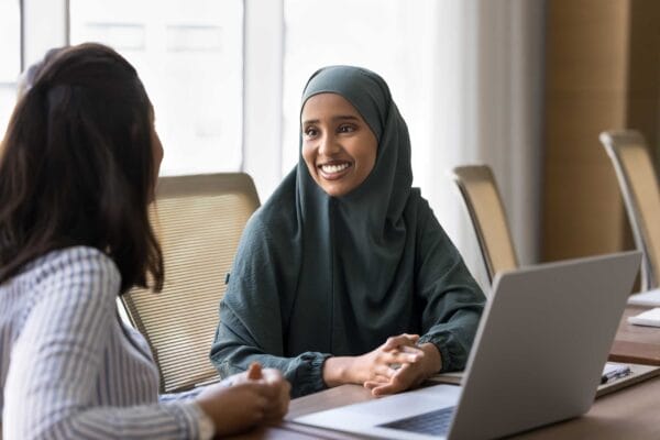 A newcomer muslim woman working with a female interpreter in front of laptop
