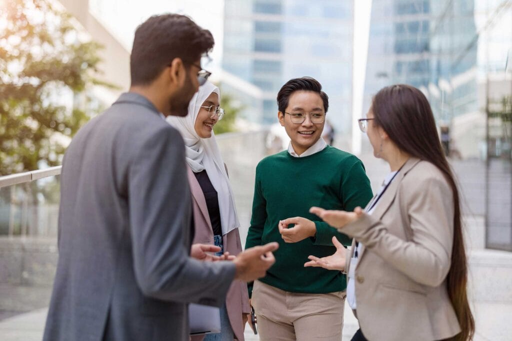 A multiethnic group wearing smart-casual attire, smiling and communicating to each other
