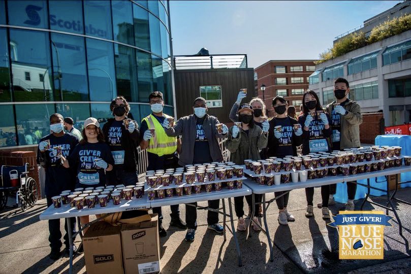 A photo of ISANS client volunteers at the Bluenose Marathon water station. They are wearing masks as it was taken in 2022 and smiling looking at the camera