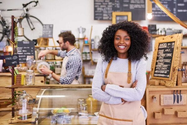 An immigrant woman smiling in front of her shop