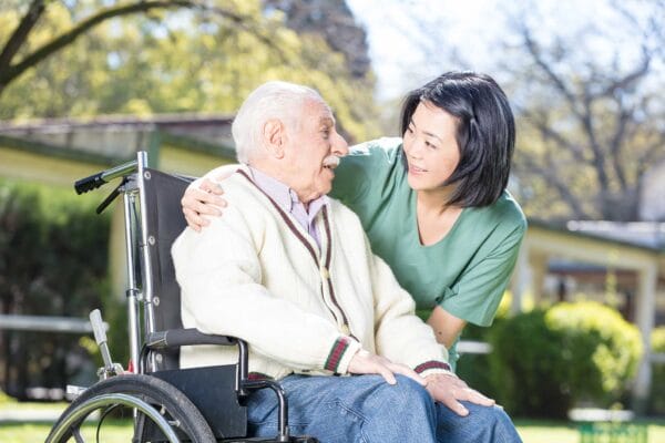 A female care aide taking care of an old man on a wheel chair