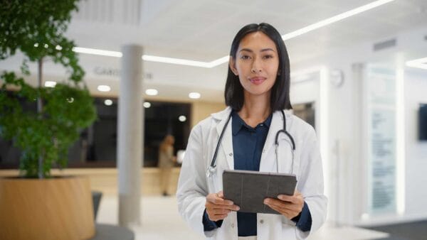 An internationally educated female doctor holding a tablet in a hospital