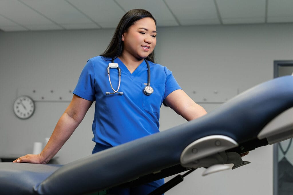 A female nurse adjusting a medical examination table