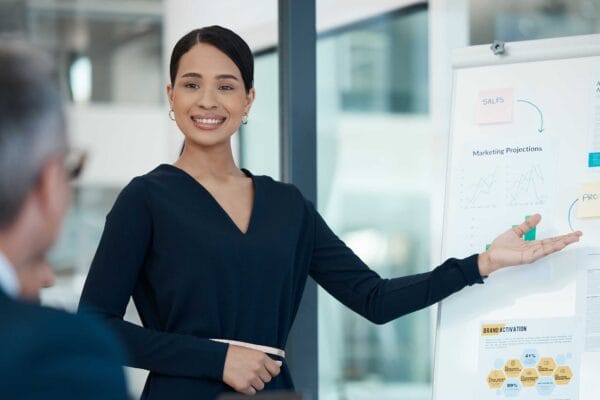 A female immigrant professional presenting her report pointing at graphics on white board