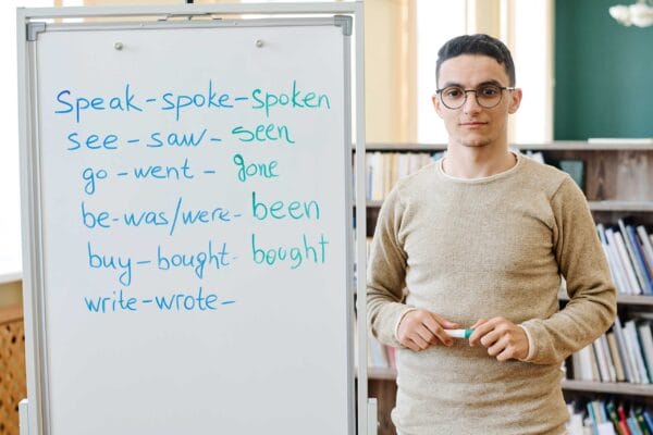 An immigrant youth standing next to a white board with English words
