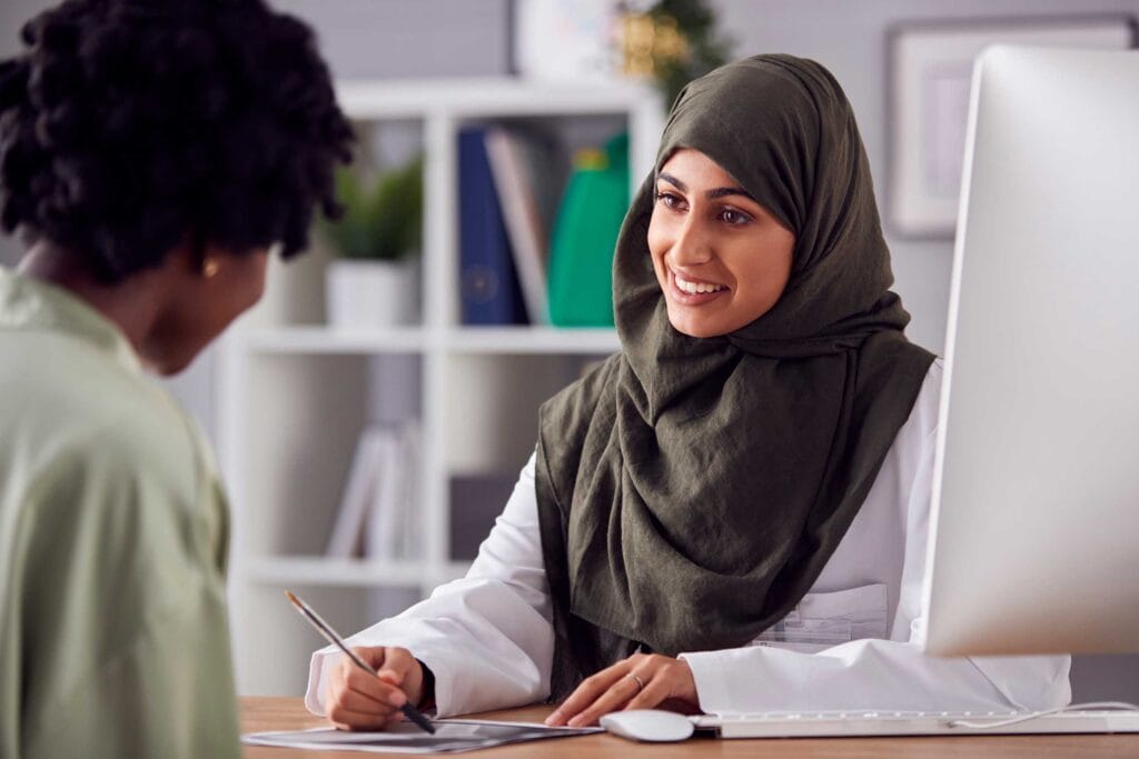 A healthcare professional muslim woman smiling and talking to a patient