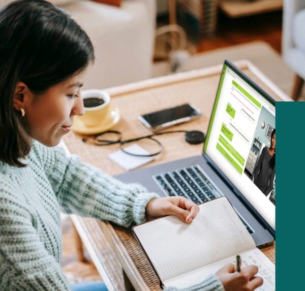 Woman taking notes in front of laptop