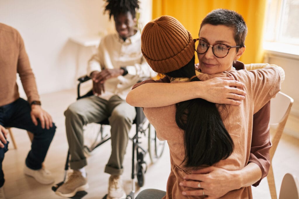 Portrait of female embracing young woman during session in support group