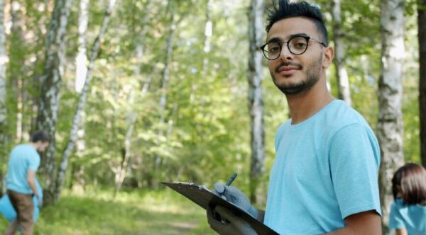 A male youth working with other youth in the forest