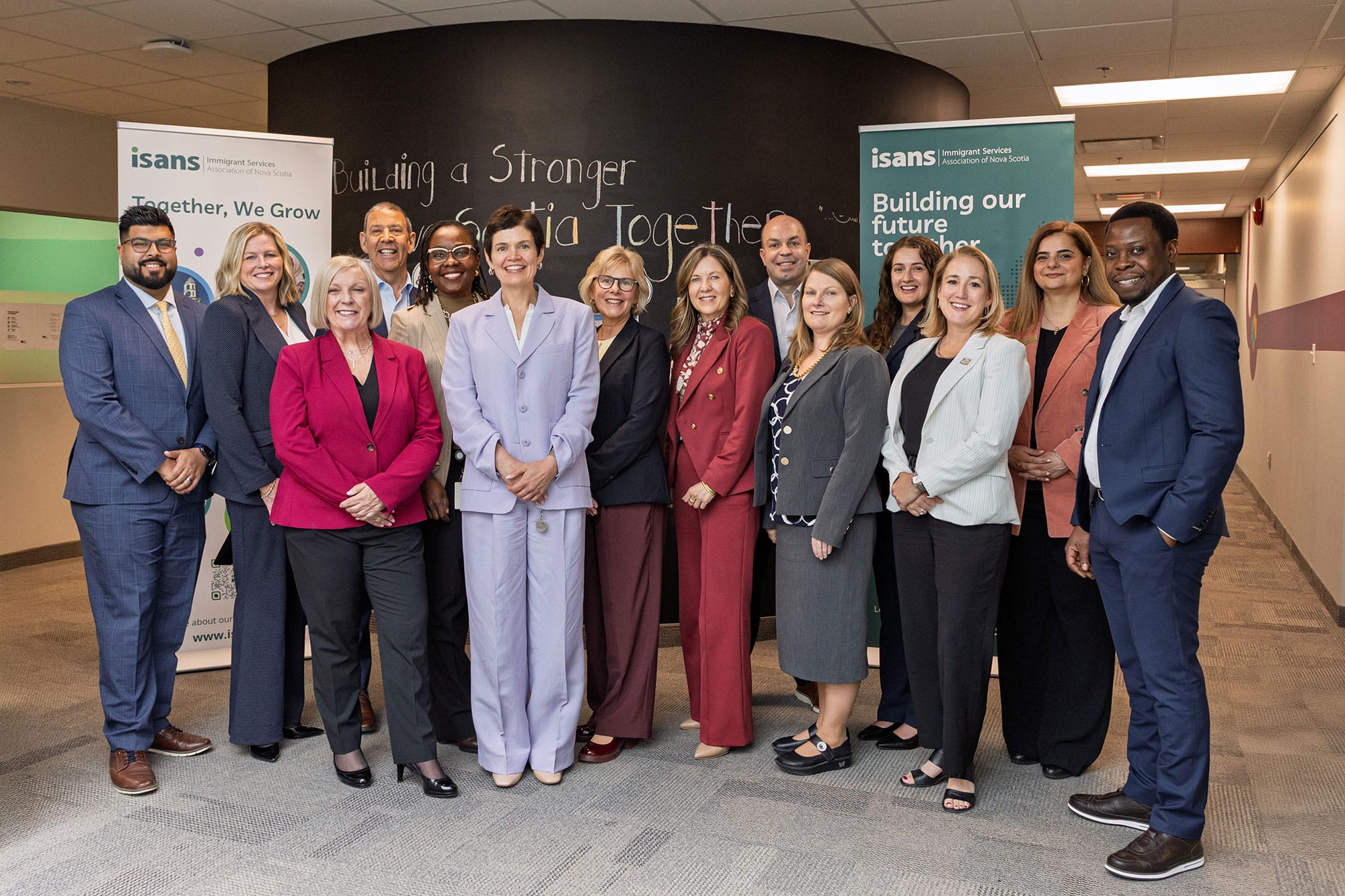 Diverse group of professionals posing in a hallway with ISANS banners in the background.
