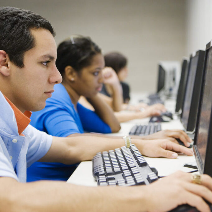 Side view of four multiethnic students using computer in lab