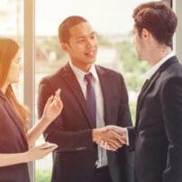 An immigrant youth wearing a suit and shaking hands with co-worker