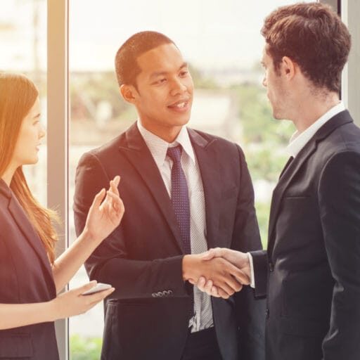 An immigrant youth wearing a suit and shaking hands with co-worker