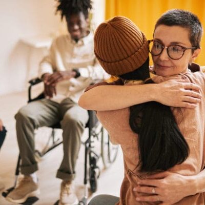 Portrait of female embracing young woman during session in support group