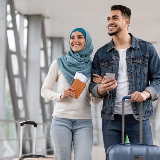 Newcomers immigrant couple happy in the airport holding their passports and luggage