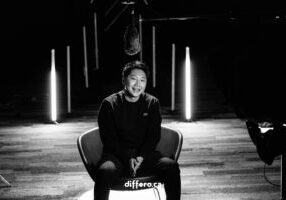 Black and White photo of the behind the scene for Chamber of Commerce Business Award shoot. Will is sitting in a chair in front of the camera