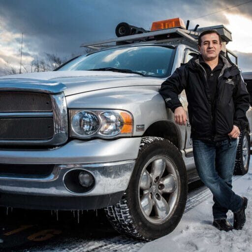 Immigrant entrepreneur, who is a business development client, standing next to his work truck