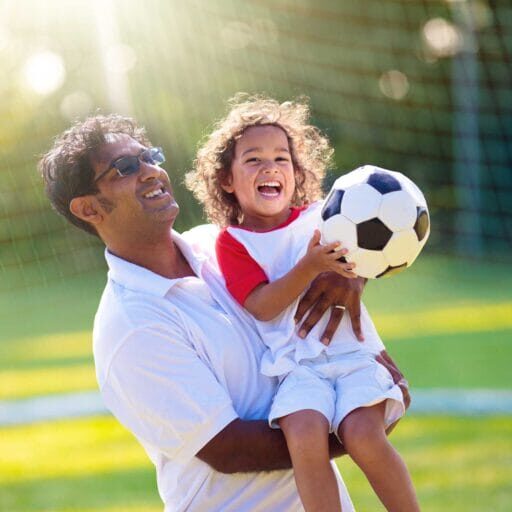 A newcomer father and his child playing soccer