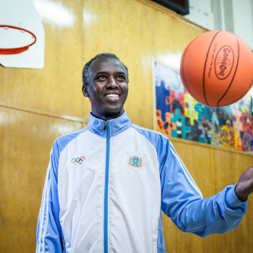 Newcomer male immigrant playing with basketball in a gym