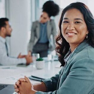 An internationally recruited employee smiling in the office in front of her laptop