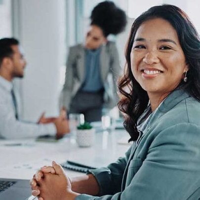 An internationally recruited employee smiling in the office in front of her laptop