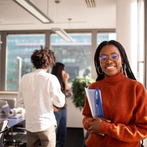 An immigrant youth, smiling, and holding a folder of documents