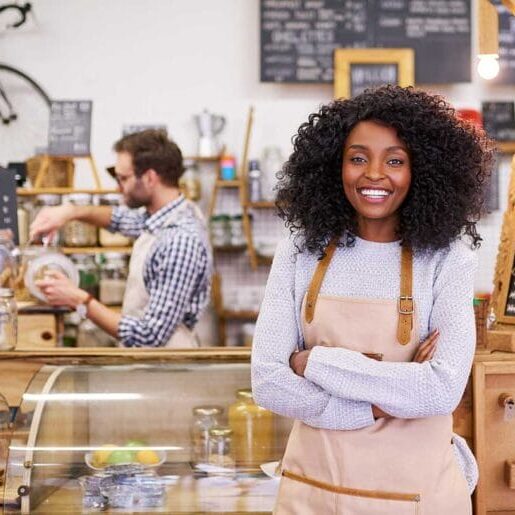 An immigrant woman smiling in front of her shop