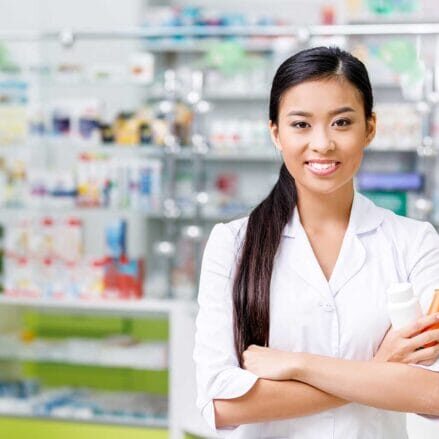 An internationally educated female pharmacist holding medicine bottles