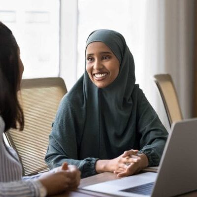 A newcomer muslim woman working with a female interpreter in front of laptop