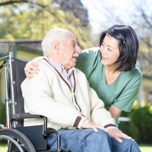 A female care aide taking care of an old man on a wheel chair