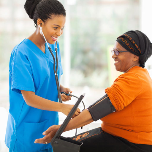 smiling african nurse checking senior patient's blood pressure