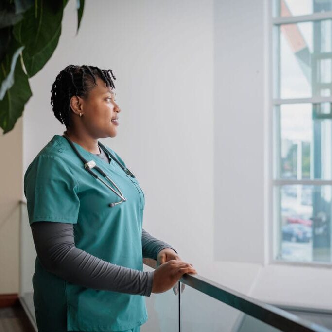 A female nurse smiling and looking out the window
