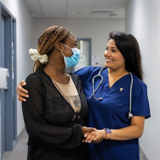 A female nurse smiling and holding a patient