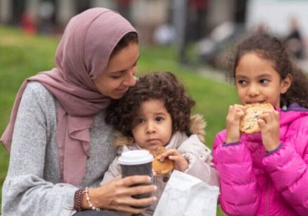 Newcomers (a woman and 2 kids) eating in the park.