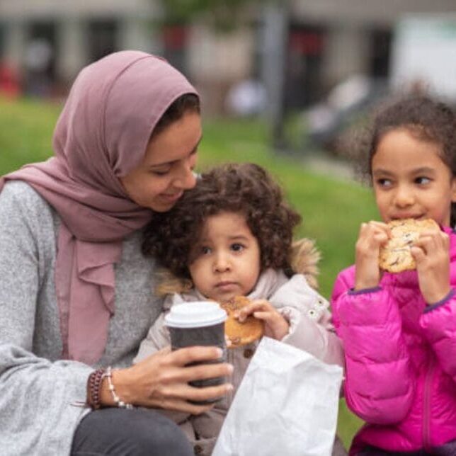 Newcomers (a woman and 2 kids) eating in the park.