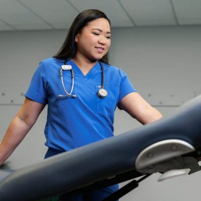 A female nurse adjusting a medical examination table