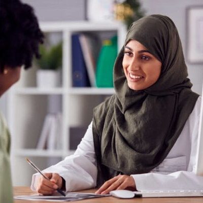 A healthcare professional muslim woman smiling and talking to a patient