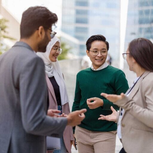 A multiethnic group wearing smart-casual attire, smiling and communicating to each other