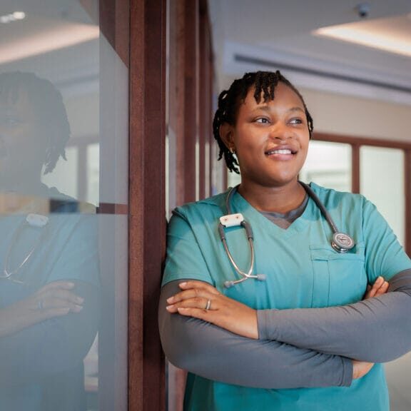 A female nurse wearing teal scrub smiling
