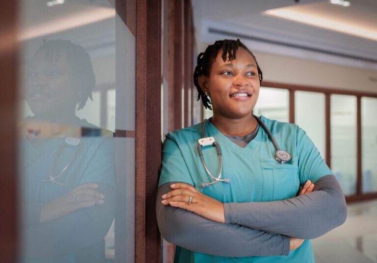 A female nurse wearing teal scrub smiling