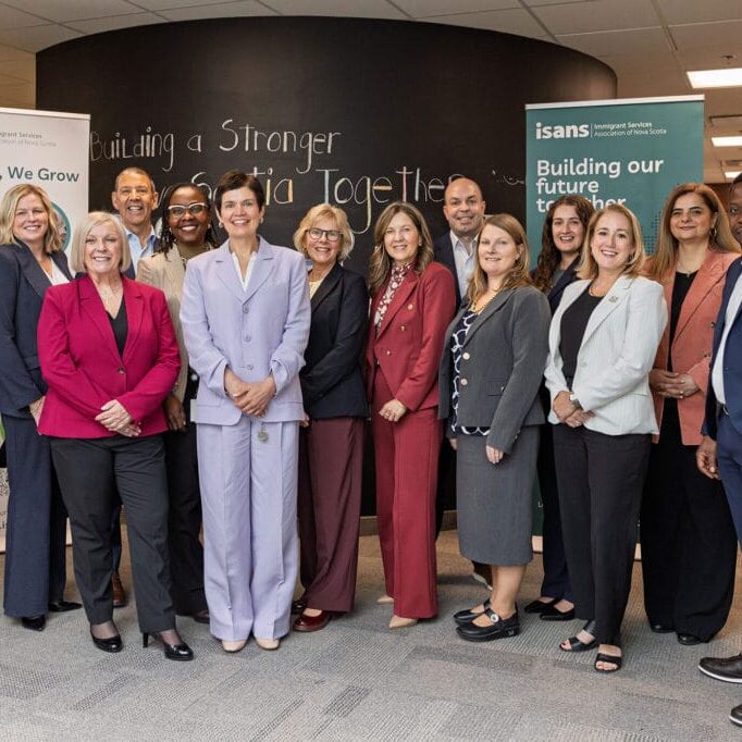Diverse group of professionals posing in a hallway with ISANS banners in the background.