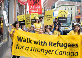 People carrying the Walk with Refugees banner and signs
